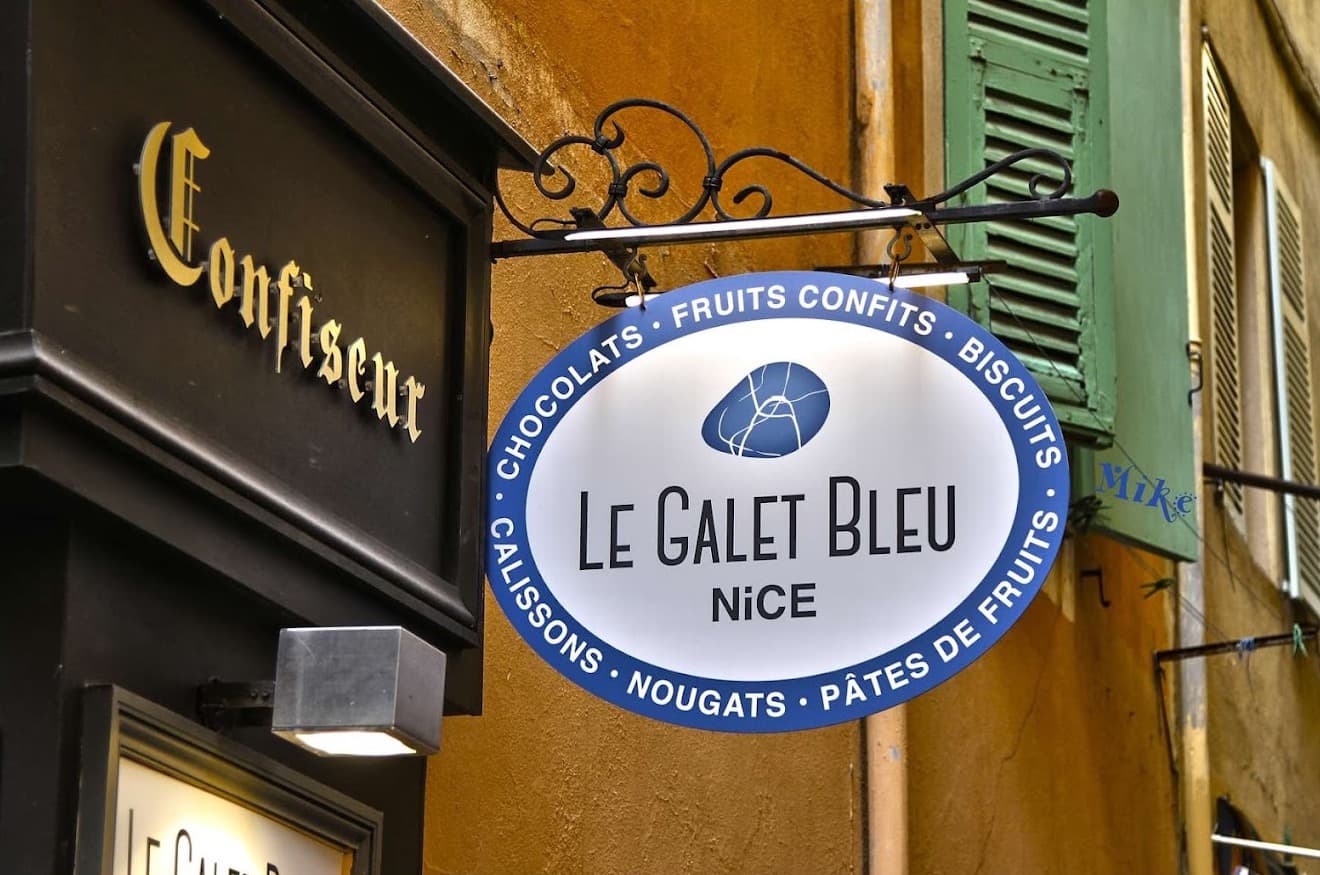 Panneau de la confiserie Le Galet Bleu suspendu dans une ruelle du Vieux-Nice